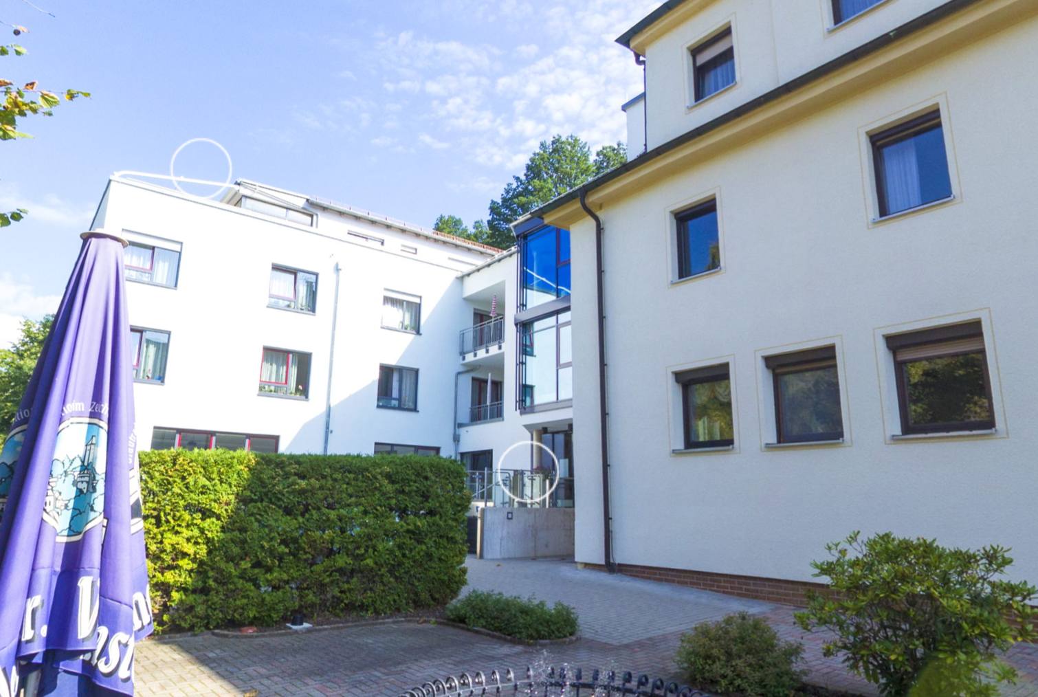 Innenhof mit Brunnen, Hecken und Sonnenschirm